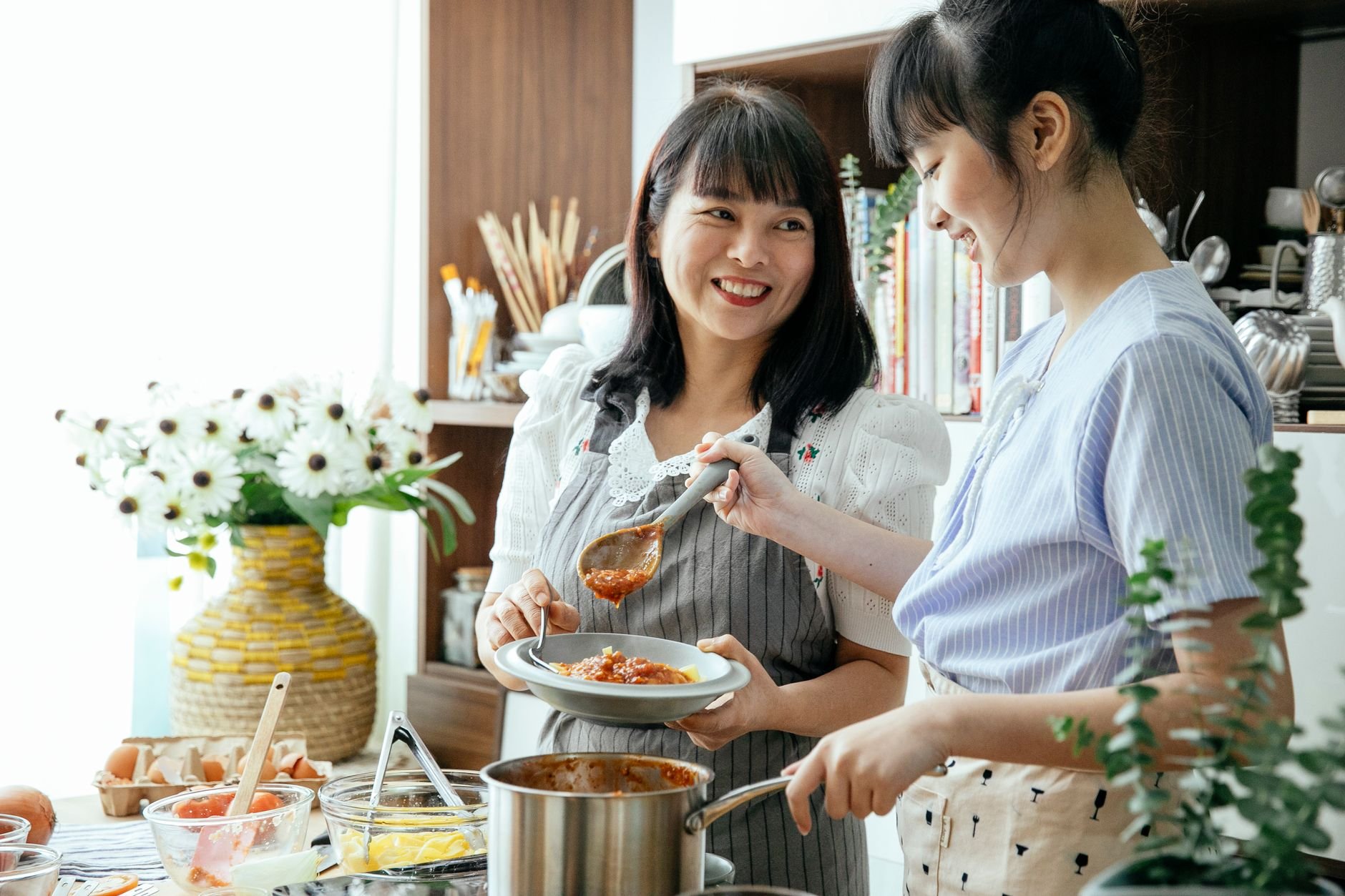 Two people cooking together in a warm kitchen, making homemade sauce.
